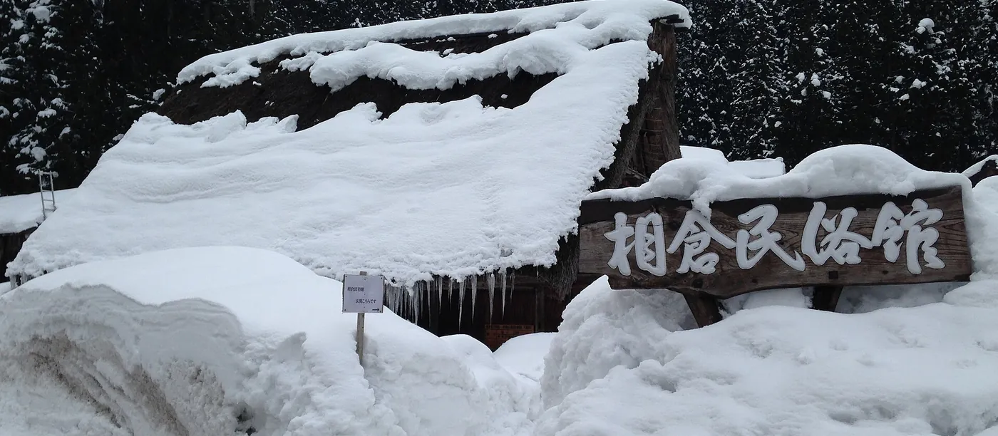 茅葺き屋根に厚く積もった雪が軒先から張り出し、つららを下げている南砺市五箇山・相倉民俗館の冬