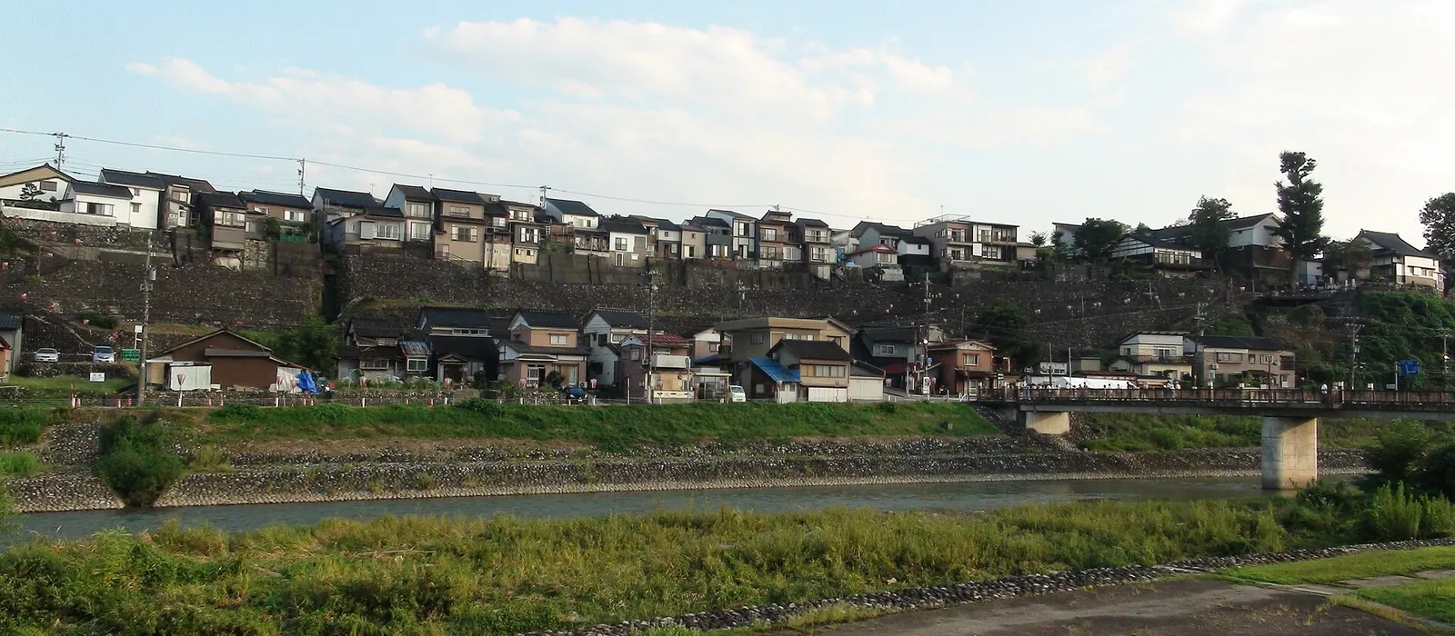 井田川越しに見た富山市八尾町の町並み。河岸段丘の石垣の上に家が並ぶ