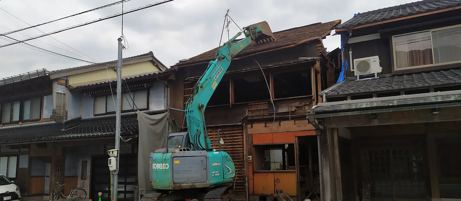 大型の工事機械で屋根から取り壊されている木造2階建て住宅の解体現場（イメージ）
