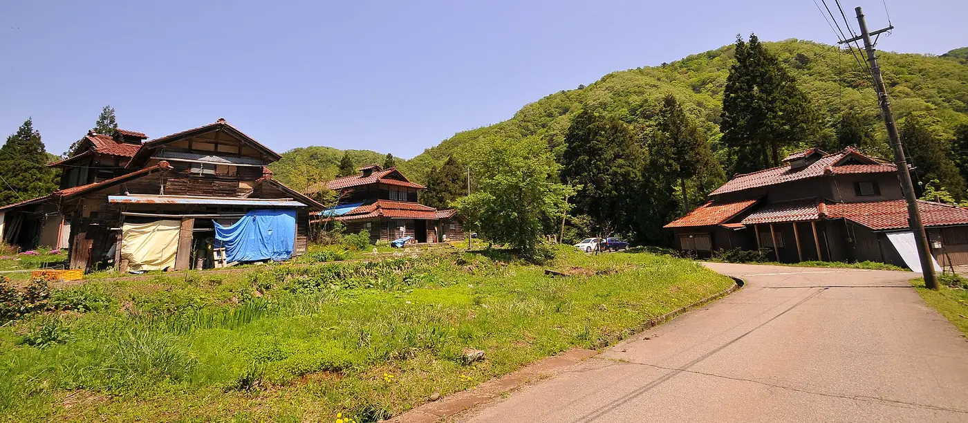 赤瓦の屋根の農家住宅が山を背にして建つ加賀市東谷地区の集落