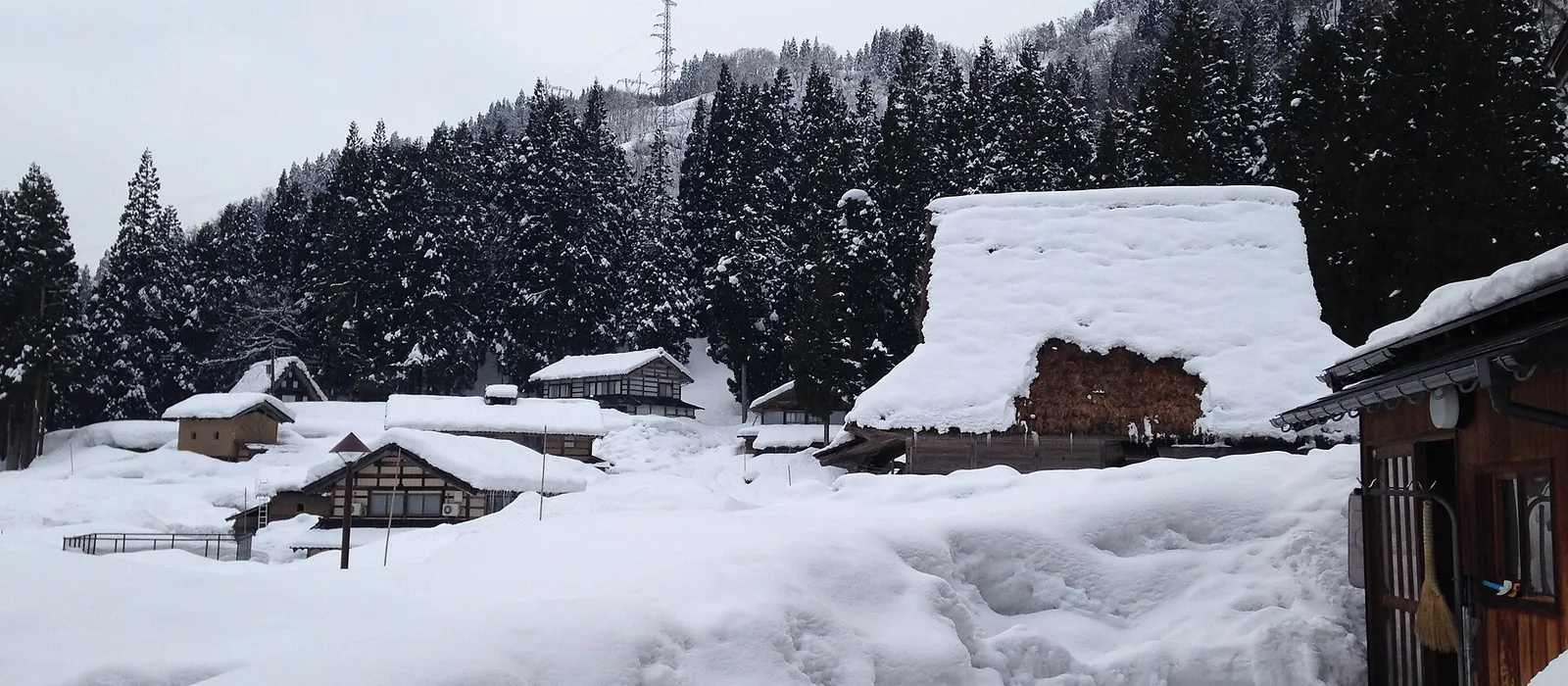 茅葺きの合掌造りと民家の屋根に雪が厚く積もり、周りが雪に埋もれた南砺市五箇山・相倉集落の冬