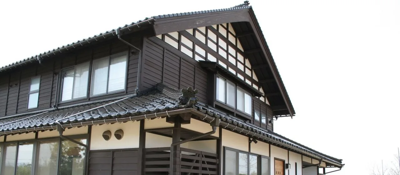 砺波地方の伝統的な農家住宅の様式「アズマダチ」の建物。妻側に格子状の貫を見せた大きな切妻屋根(となみ散居村ミュージアム)