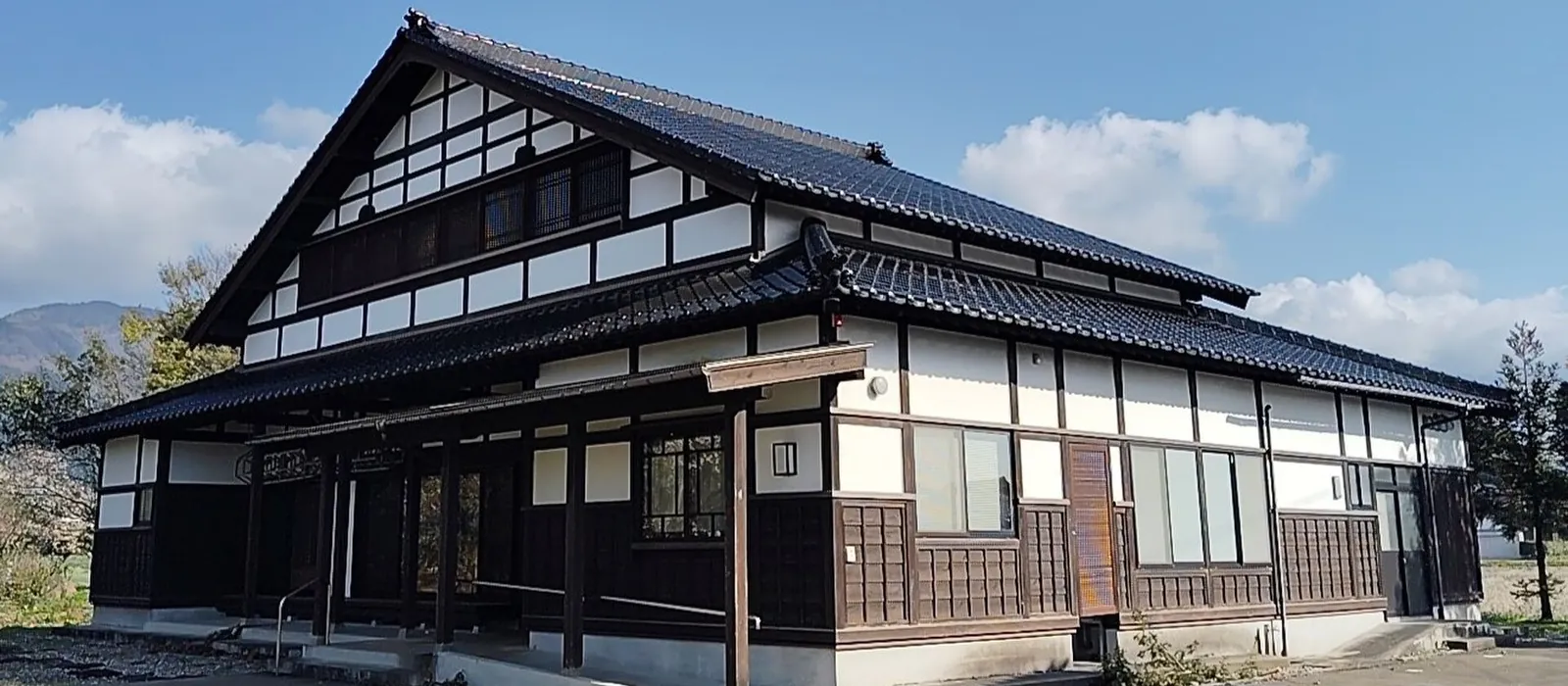 大きな切妻屋根と格子状の貫を見せる砺波地方のアズマダチの建物（南砺市の見学施設あずまだち高瀬）